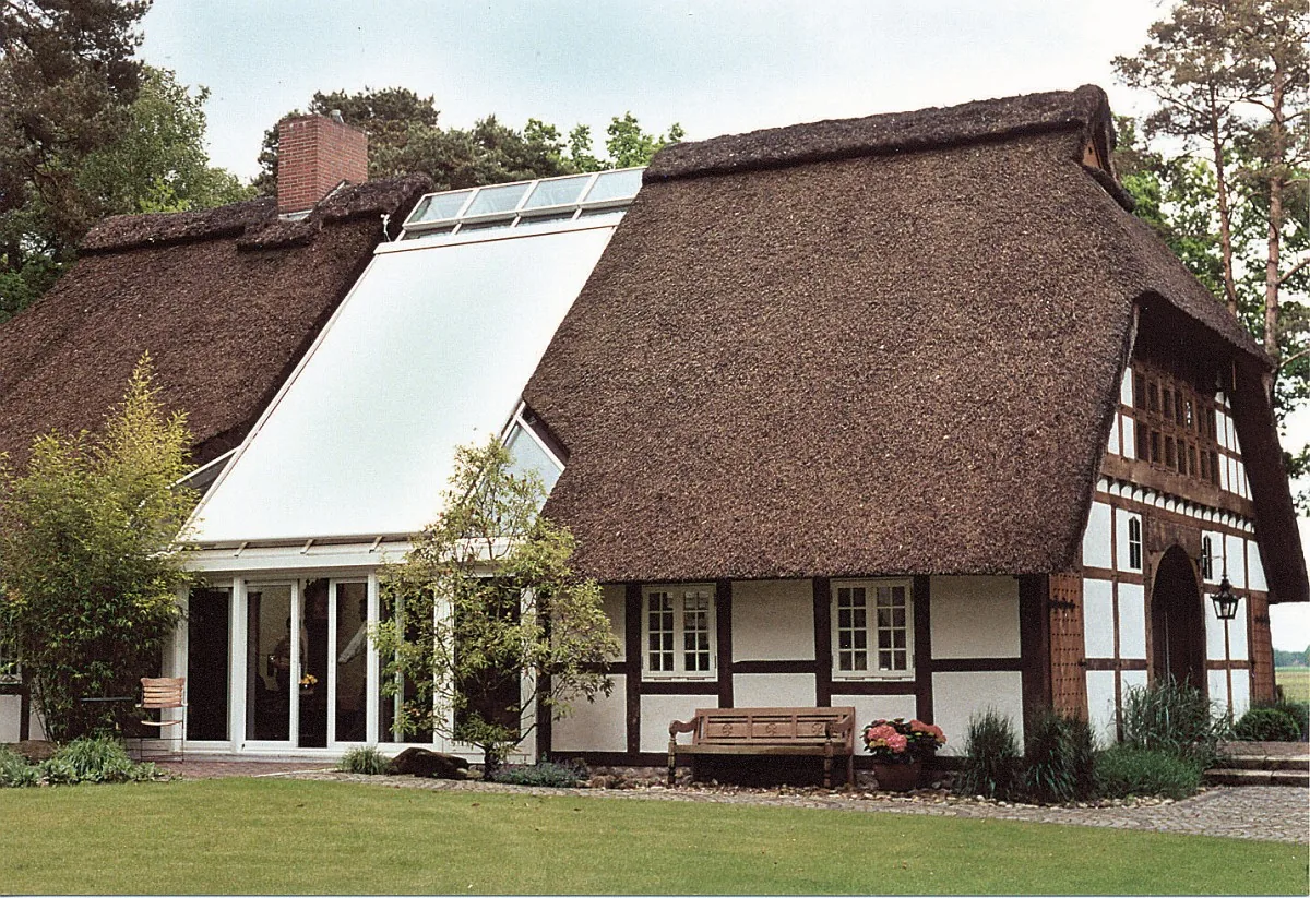 Wintergarten mit heller Markise auf dem Glasdach an einem Reetdachhaus