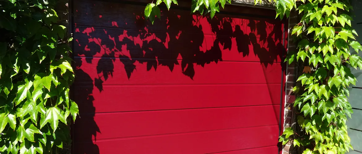 Rotes Garagentor, umrahmt von wildem Wein an der Hauswand