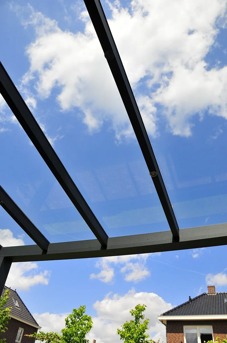 Blick von unten in ein Glasdach mit Aluminiumsparren vor blauem Himmel