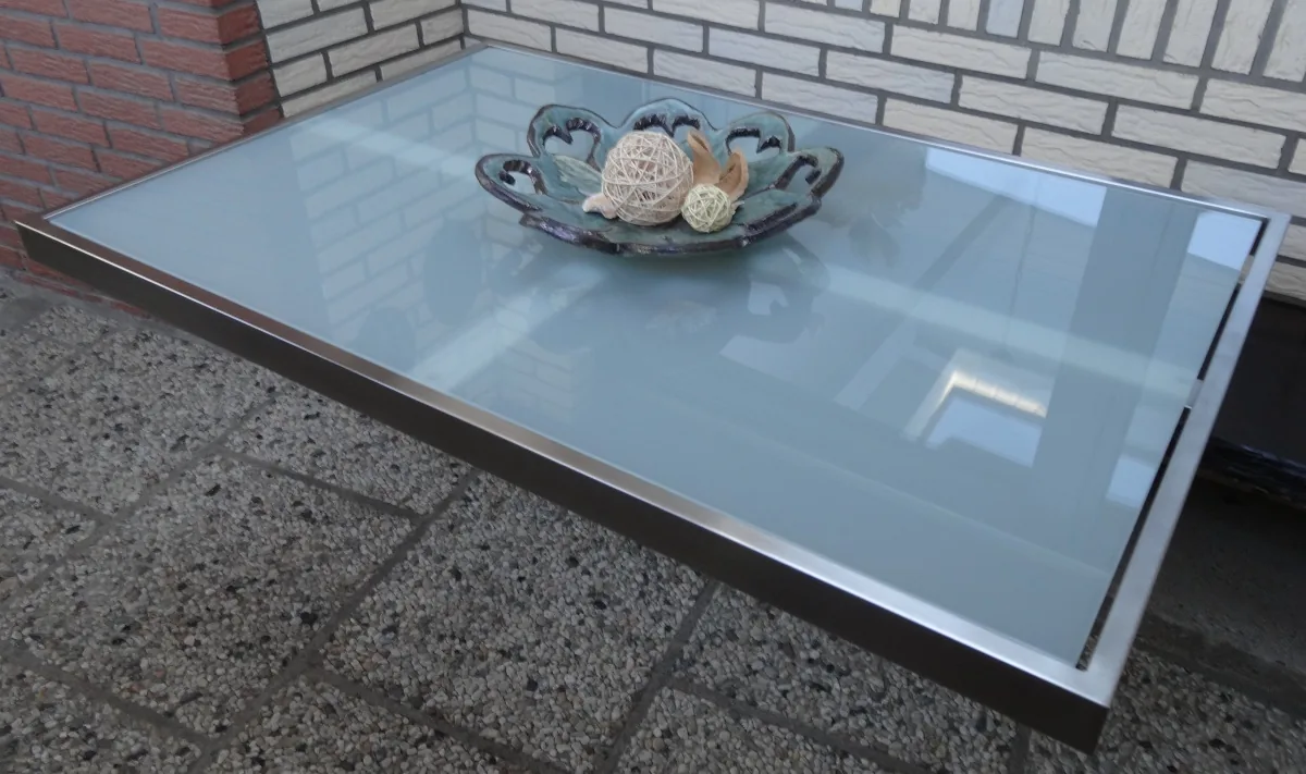 Tisch mit Glasplatte und Edelstahlrahmen auf einer Terrasse