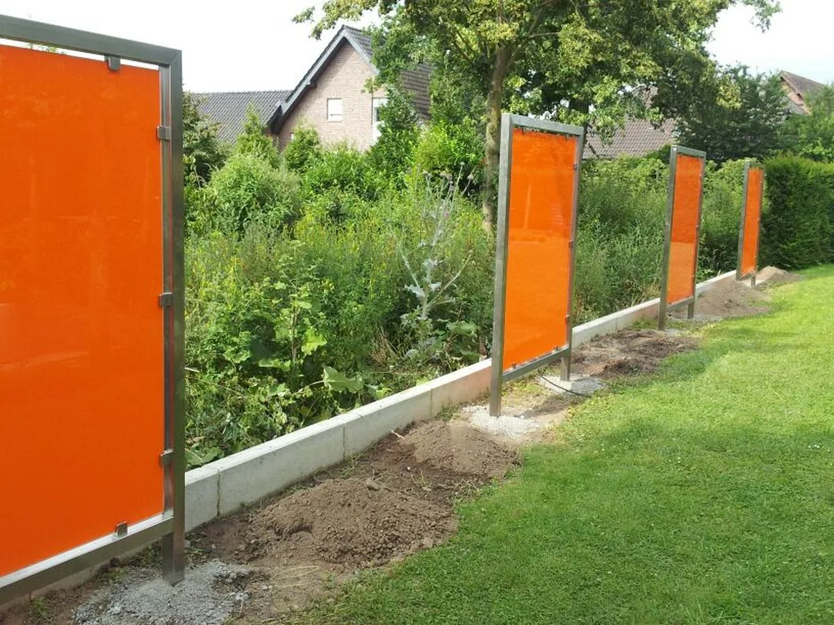 Sichtschutzzaun mit orangefarbenen Feldern zwischen Metallpfosten, Detail
