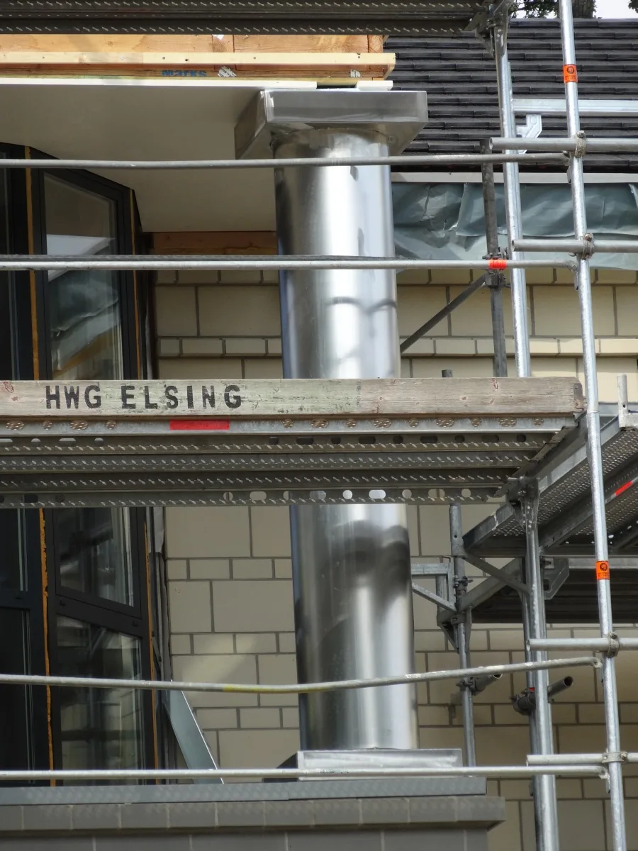 Abgasrohr aus Edelstahl an einer Hausfassade, montiert vom Gerüst