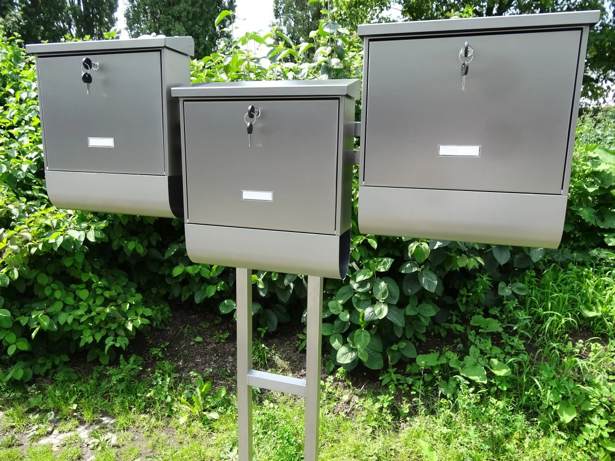 Briefkastenanlage aus Edelstahl mit vier Kästen vor einer Hecke