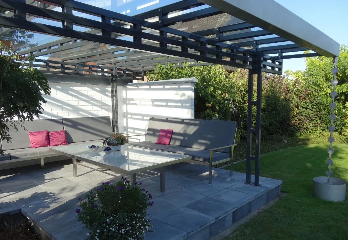 Freistehende Überdachung über einer Terrasse mit Loungemöbeln und rosa Kissen